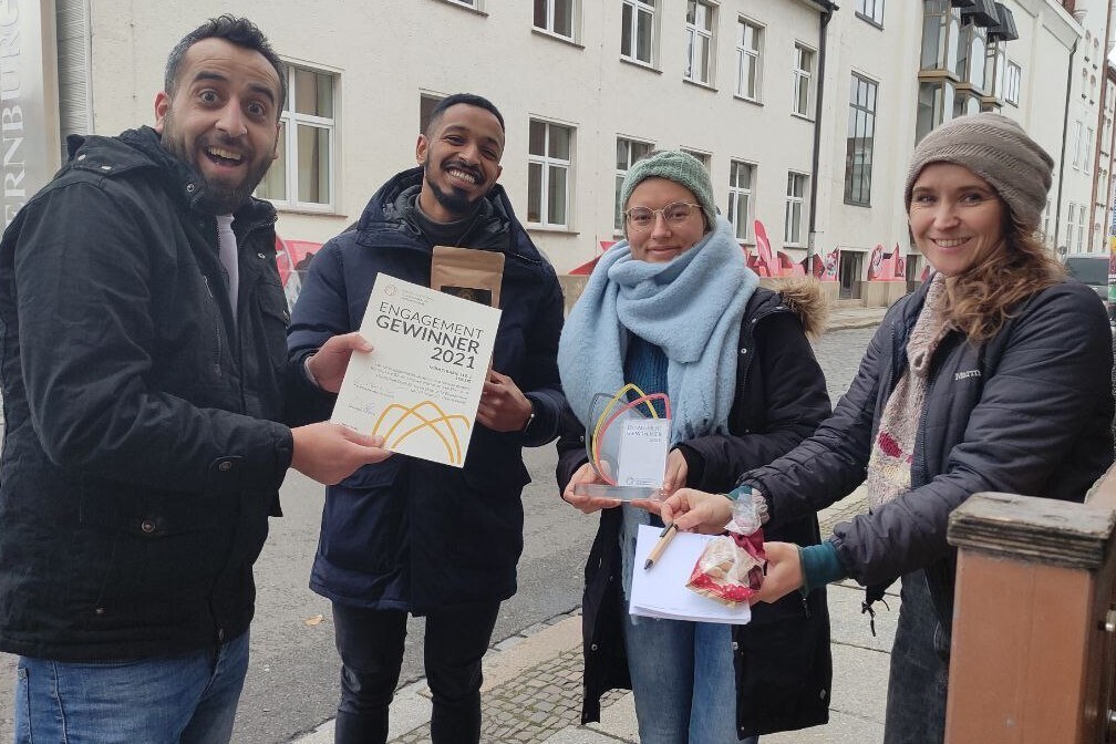 Vier Menschen halten Geschenke und Urkunde des Preises.