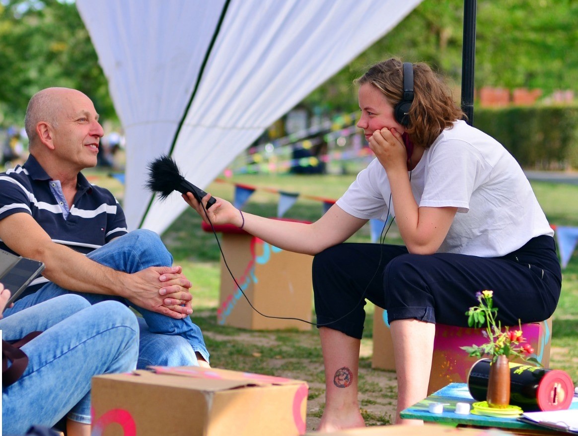 eine Person (weiblich gelesen) interviewt eine männlich gelesene Person